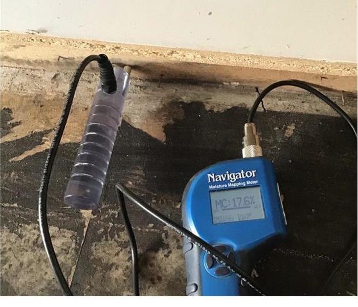 a blue small equipment with a prong stuck in the drywall