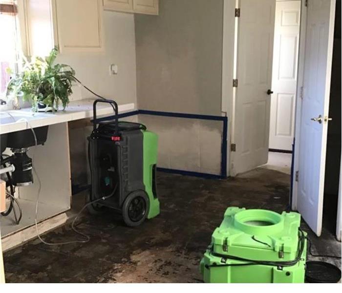 room with two green machines and flooring that has been removed