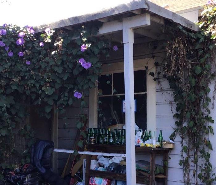 house with vines and flowers surrounding it glass bottles on top of a table