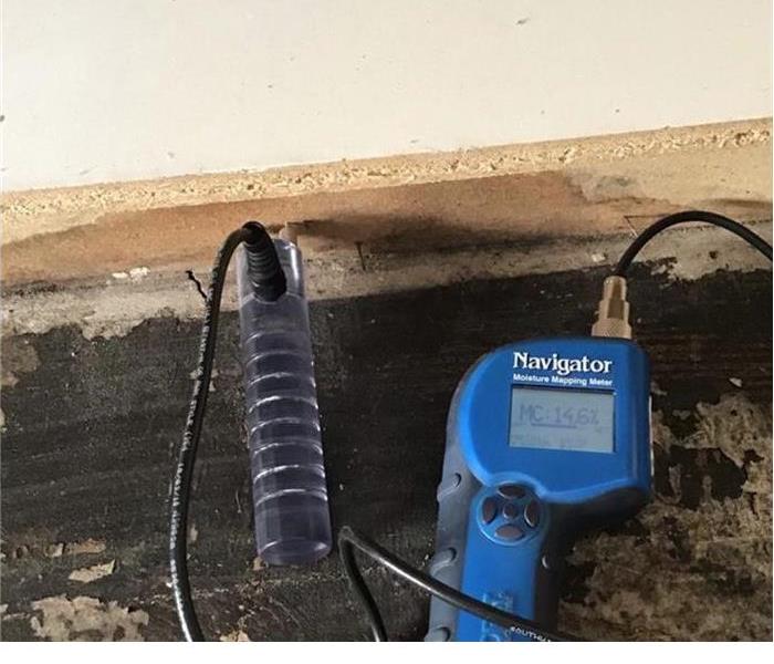 bare floor with a blue moisture meter within the wall