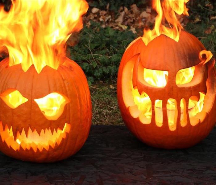 Two carved pumpkins that are up in flames.